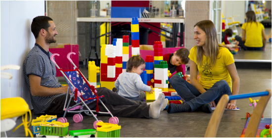 Des parents discutent pendant que des enfants jouent au Carrefour des Petits Soleils